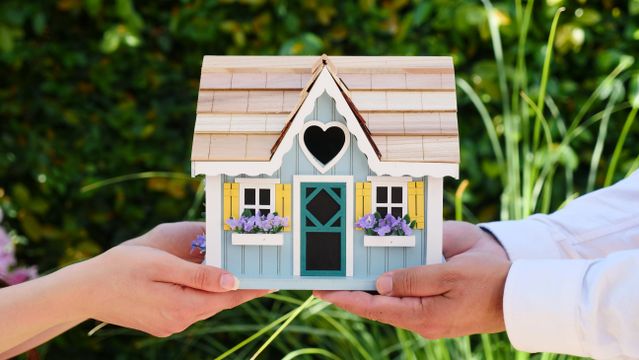 two people holding a home figurine